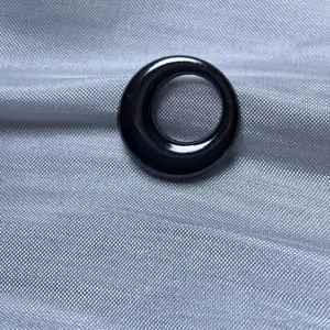 Vue macro d'une perle de bijoux DIY circulaire noire brillante sur tissu argenté