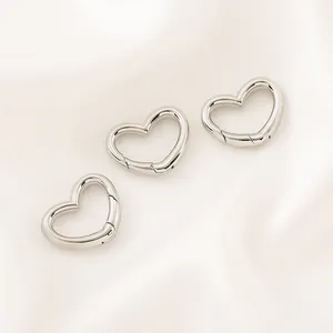 Gros plan de fermoirs à ressort en forme de cœur argentés pour projets de bijoux DIY.