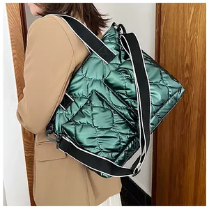 Detail view of a green quilted space cotton tote bag with a wide black shoulder strap.