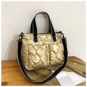 Detailed view of the gold quilted texture and wide striped straps of the tote bag.