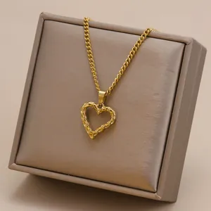 Close-up view of a gold-plated heart pendant with hammered texture on a curb chain