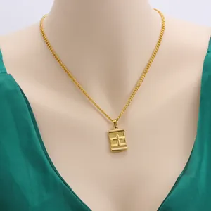 Close-up of gold stainless steel necklace with rectangular cross pendant on model.