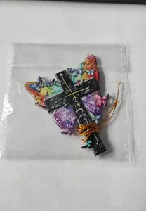 Primer plano del adorno navideño de mariposa y cruz de acrílico en una bolsa de embalaje transparente.