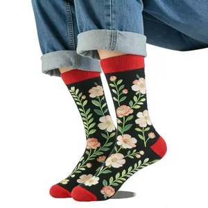 Détail de chaussettes jacquard fleuries avec accents rouges portées sur un jean bleu