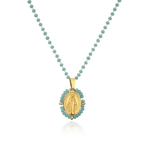 Detailed view of a gold-plated Virgin Mary oval pendant with light blue beads.