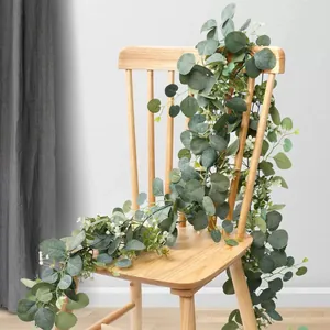 Detailansicht einer künstlichen Eukalyptus-Girlande mit weißen Blumen auf einem Holzstuhl.