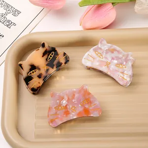 Detailed view of three cat-shaped acetate hair claw clips in marble and tortoiseshell patterns.