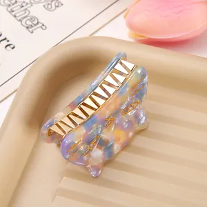 Macro detail of a cute marbled acetate cat-shaped hair claw clip on a beige tray.