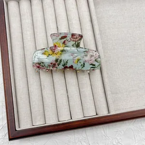 Dettaglio di una pinza per capelli floreale vintage su un vassoio per gioielli grigio