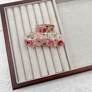 Primo piano di un fermaglio per capelli vintage con motivi di rose rosa.