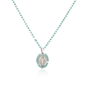 Detailed macro view of turquoise beaded chain with silver Virgin Mary pendant necklace