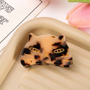 Detailed macro shot of a cute acetate cat-shaped hair claw clip with gold-tone accents.