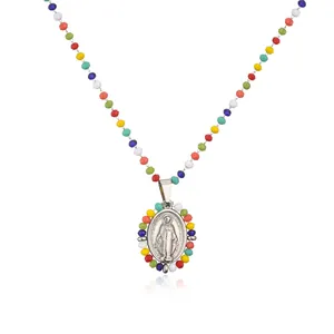 Detailed view of colorful faceted beaded necklace featuring a religious oval medal pendant