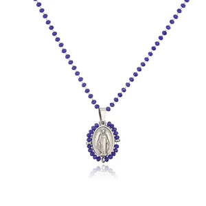 Detail of stainless steel oval Virgin Mary pendant necklace with blue faceted beads.