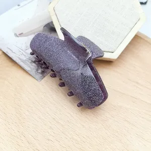 Macro view of a sparkling purple acetate hair claw clip resting on a wooden display