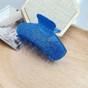 Close-up of blue glitter acetate cat-ear hair claw clip on wooden background