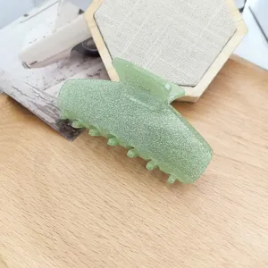 Close-up of a green cat-ear shaped acetate hair claw clip with a shimmering glitter finish