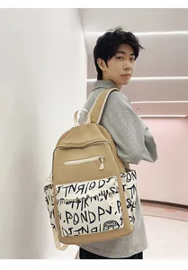 Back view of a trendy khaki student backpack with graffiti print worn by a model