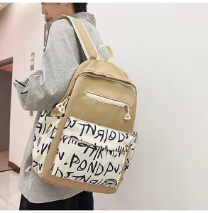Detailed view of the trendy khaki student backpack with graffiti print worn by a model
