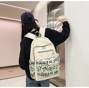 Detail view of a trendy cream backpack with graffiti print worn by a model
