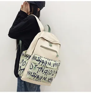 Close-up of a student wearing a large capacity graffiti print backpack in beige and green