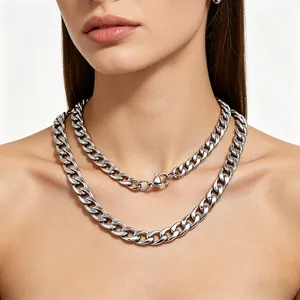 Detailed shot of layered chunky silver stainless steel Cuban link necklaces on neck.