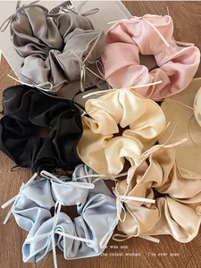 Detailed view of satin ballet ribbon bow scrunchies in various soft pastel colors.
