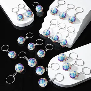 Groupe de porte-clés boule disco irisés sur des supports géométriques blancs.