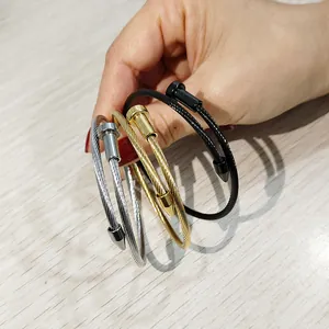 Primo piano di braccialetti in filo di acciaio inossidabile a forma di chiodo in oro e nero.