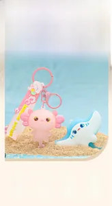 Cute axolotl and stingray cartoon keychain charms displayed on a beach sand background