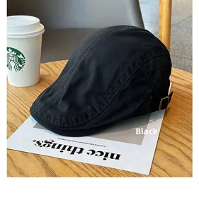 Side view of a vintage black flat cap with adjustable metal buckle on wooden table