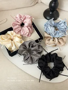 Detail view of satin ballet-style scrunchies with delicate ribbon bows in multiple colors