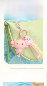 Close-up detail of a cute pink axolotl keychain pendant hanging on a green bag