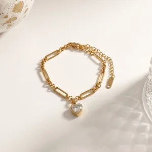 Detail van gouden titanium stalen armband met hartvormige kristallen hanger aan een schakelketting