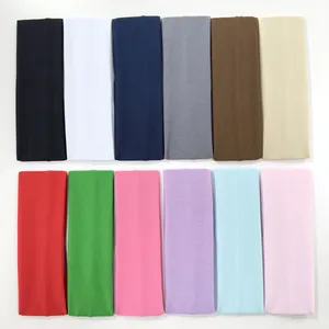 Wide elastic sports headbands in 12 solid colors arranged neatly on white surface
