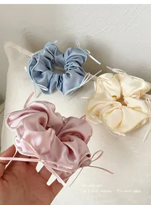 Detailed view of satin scrunchies with ribbon bows in soft blue, pink, and cream hues