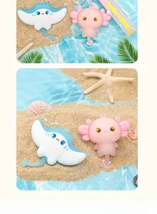 Detail view of cute cartoon manta ray and axolotl sea animal keychains on beach sand