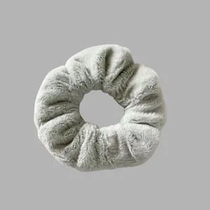 Détail macro d'un chouchou en peluche gris doux montrant la texture élégante et floue