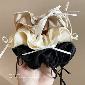 Three elegant ballet style satin scrunchies with ribbon bows in beige cream and black