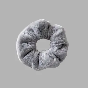Détail d'un chouchou en peluche gris doux avec une texture en fausse fourrure moelleuse