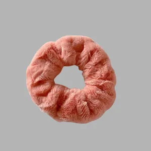 Vue détaillée d'un chouchou en peluche rose doux soulignant la texture duveteuse et l'élastique