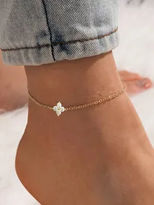 Close-up detail of a gold-plated sterling silver anklet with a diamond clover charm