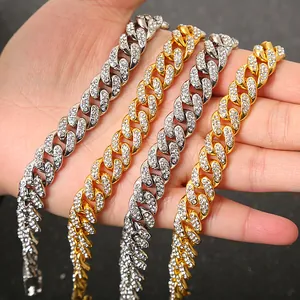 Detailed view of four iced out gold and silver Cuban link necklaces held in hand