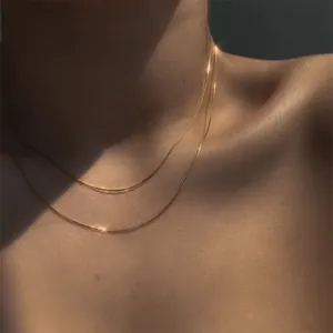 Gros plan élégant d'un collier double couche en chaîne serpent dorée sur un mannequin