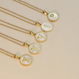 Détail de colliers dorés circulaires avec pendentifs alphabet en incrustation de nacre
