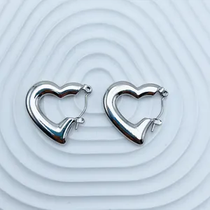 Detailed macro view of polished silver heart-shaped stainless steel hoop earrings