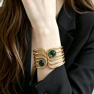 Vintage gold-plated geometric cuff bracelet with deep green stones on model wrist