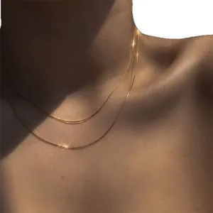Élégant collier à double épaisseur en maille serpent dorée porté sur une clavicule