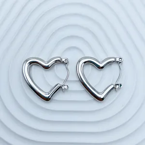 Macro view of polished silver-tone stainless steel heart-shaped hoop earrings on white