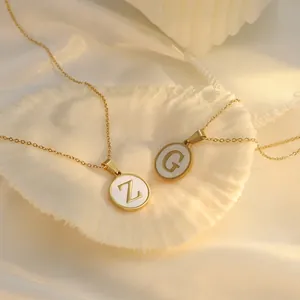 Vue macro détaillée de colliers pendentifs en nacre et or avec les initiales 'Z' et 'G'.